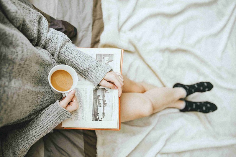 woman taking a coffee and reading a book at home